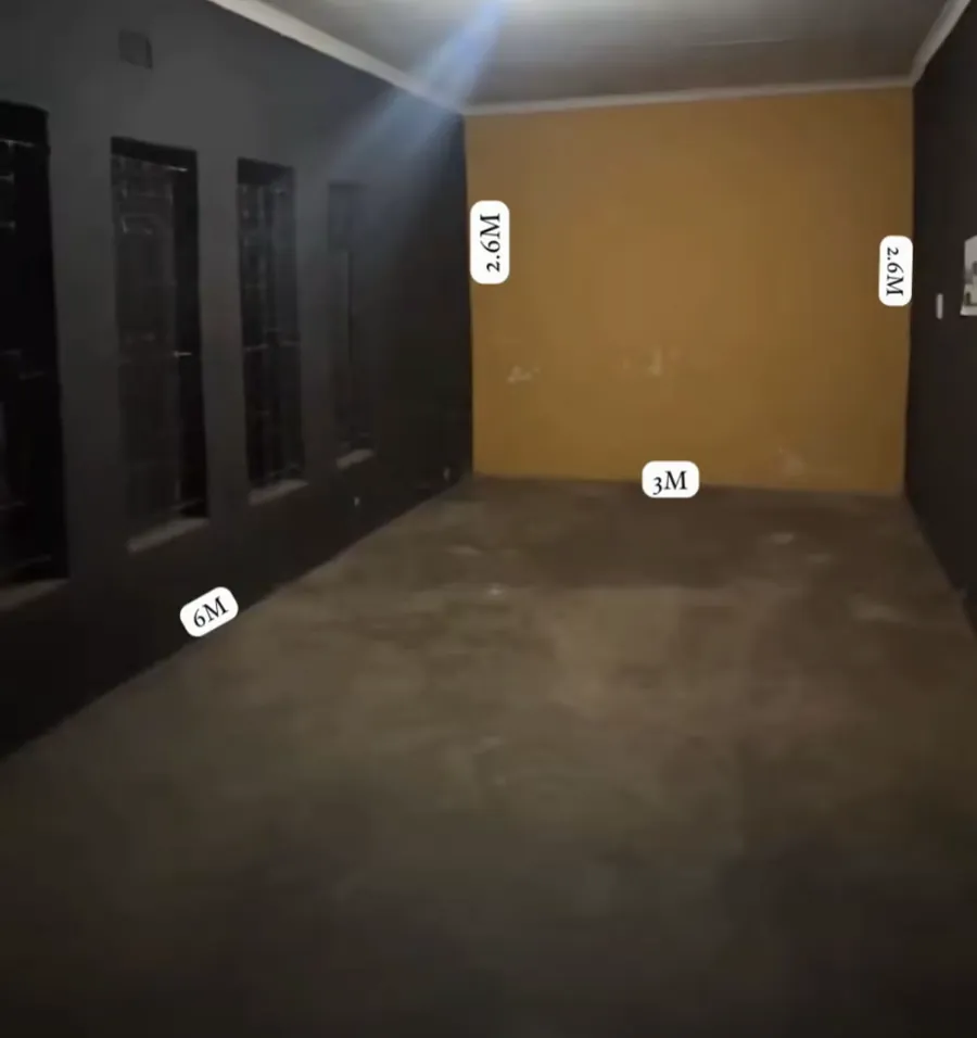 An empty garage with dark walls and a mustard back wall, measured 6m by 3m by 2.6m
